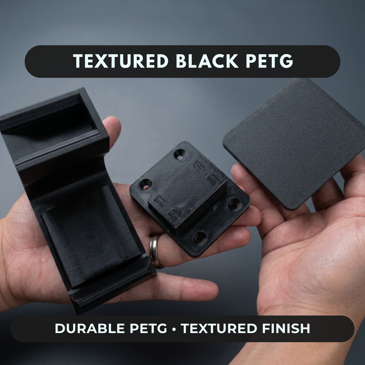 Hands holding the textured black PETG headset caddy hook and mount bases