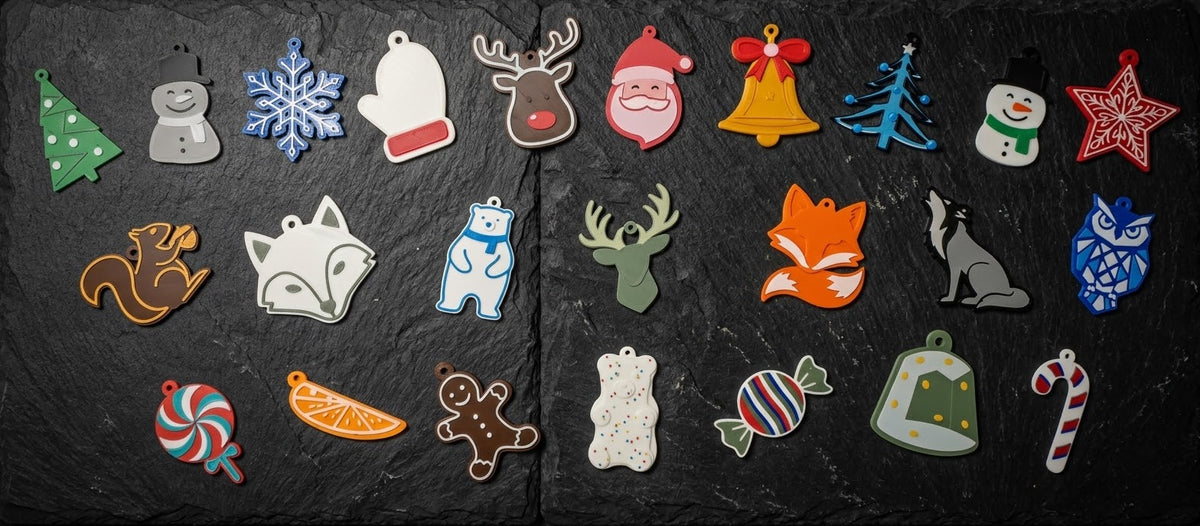 Full 24-piece 3D printed Christmas ornament collection laid out on slate